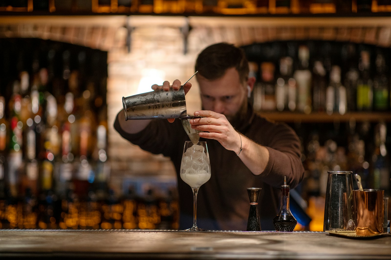 Bartender preparing a cocktail at a dim lounge bar, illustrating the liquor liability and dram shop exposure a hookah lounge takes on once it serves alcohol