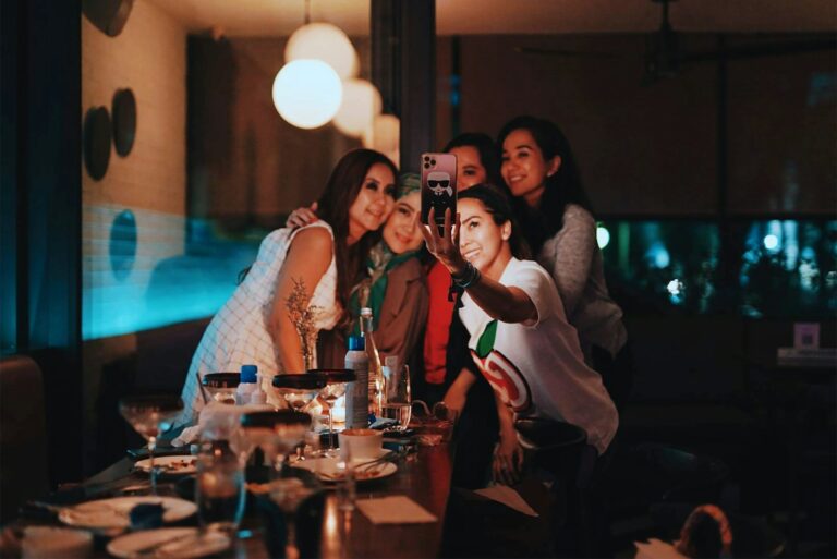 A group of patrons toasting cocktails at a busy late-night bar, illustrating the Georgia dram shop and liquor liability exposure Atlanta nightlife venues take on the moment they over-serve a guest