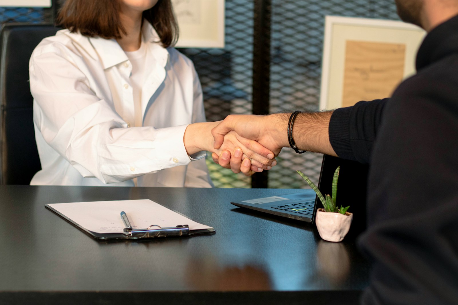 Two people shaking hands across a desk after an insurance meeting, illustrating why Atlanta bar, club, and hookah lounge owners get better premiums working with a broker who knows the surplus lines hospitality market