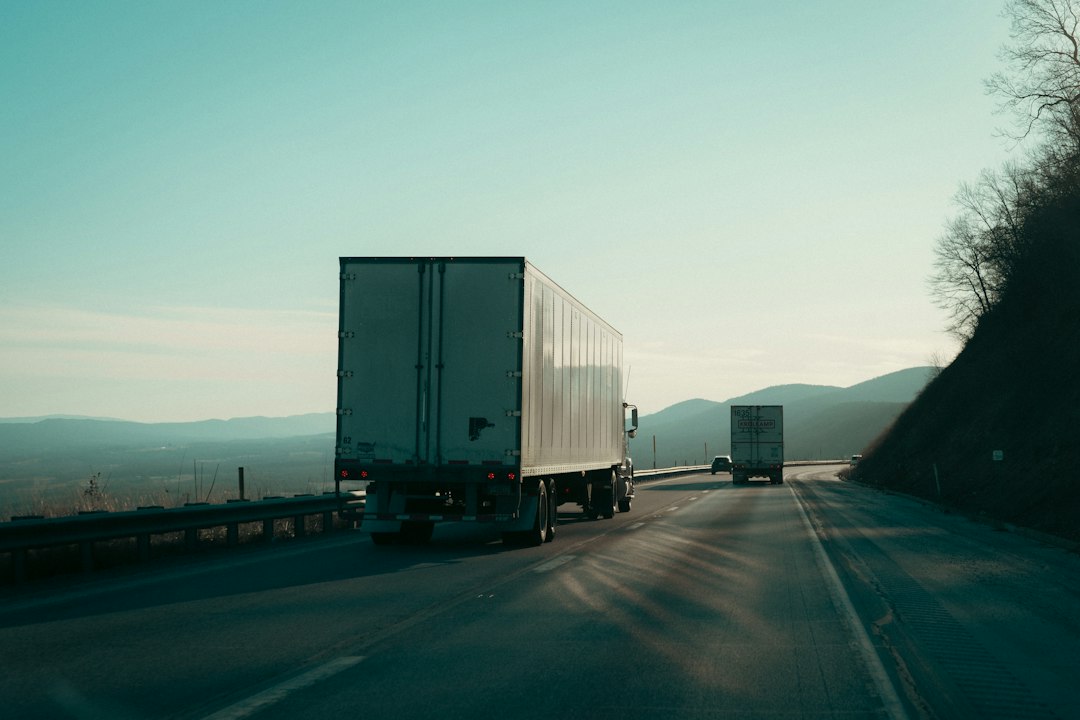 Commercial trucks traveling on a highway with mountains in the background
